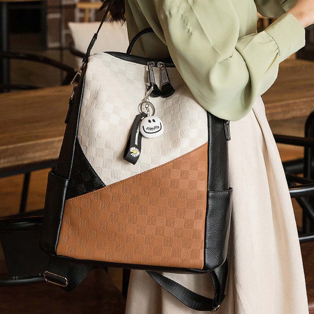 cream-black-brown women's faux leather backpack worn on shoulder in a coffee shop scene