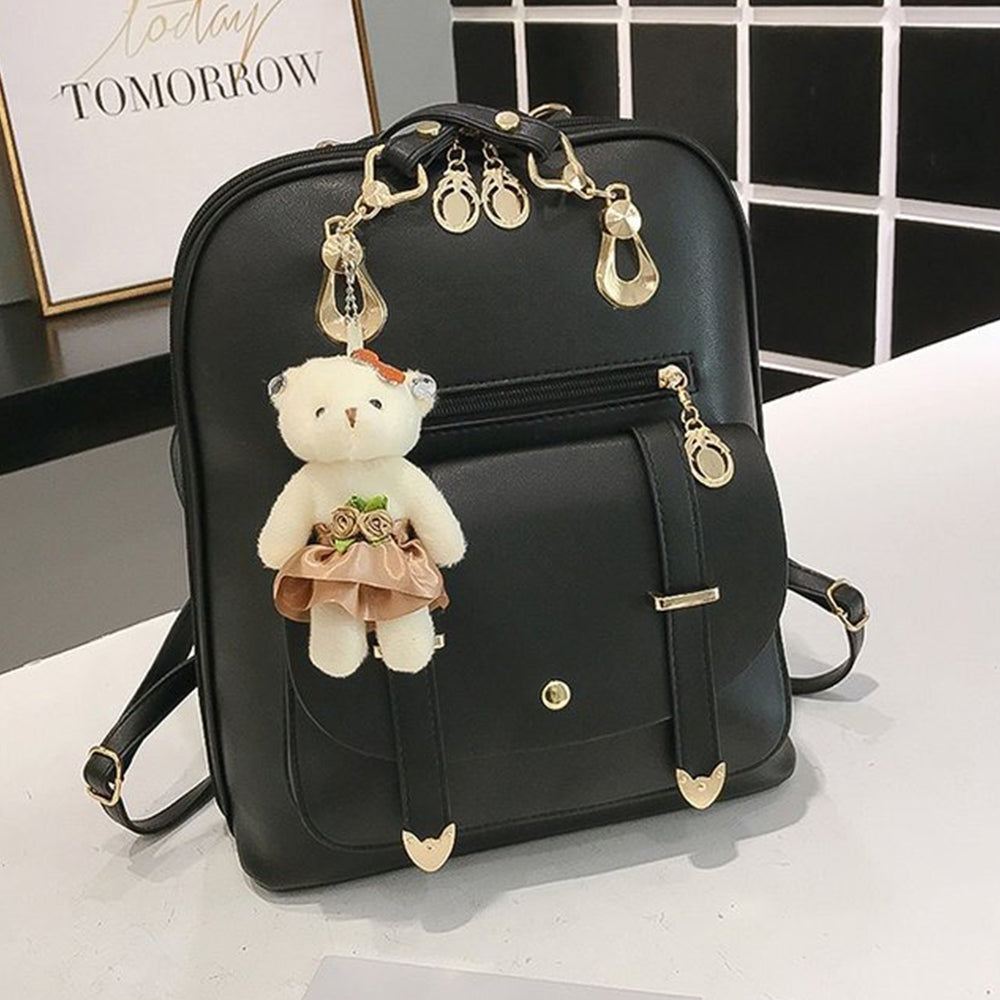 black compact women's backpack in a product photo with teddy bear charm and top handle