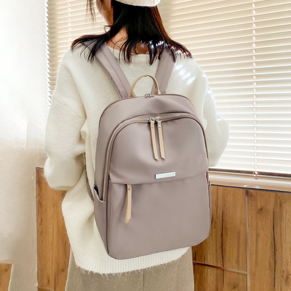 Grey-beige women's laptop backpack worn on a model from the back with a zippered front pocket